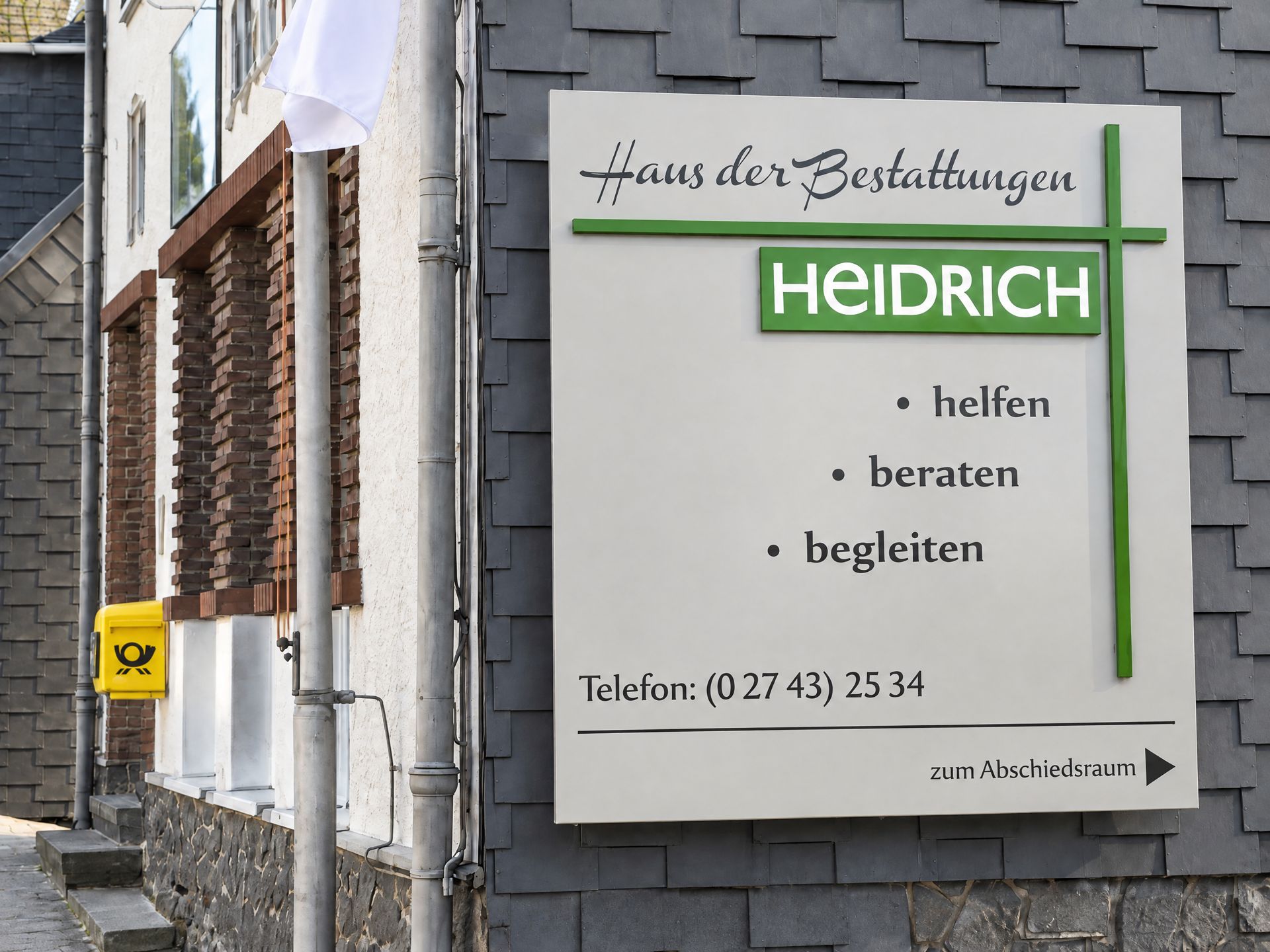 Schild „Haus der Bestattungen Heidrich – helfen, beraten, begleiten“ am Bestattungshaus in Daaden