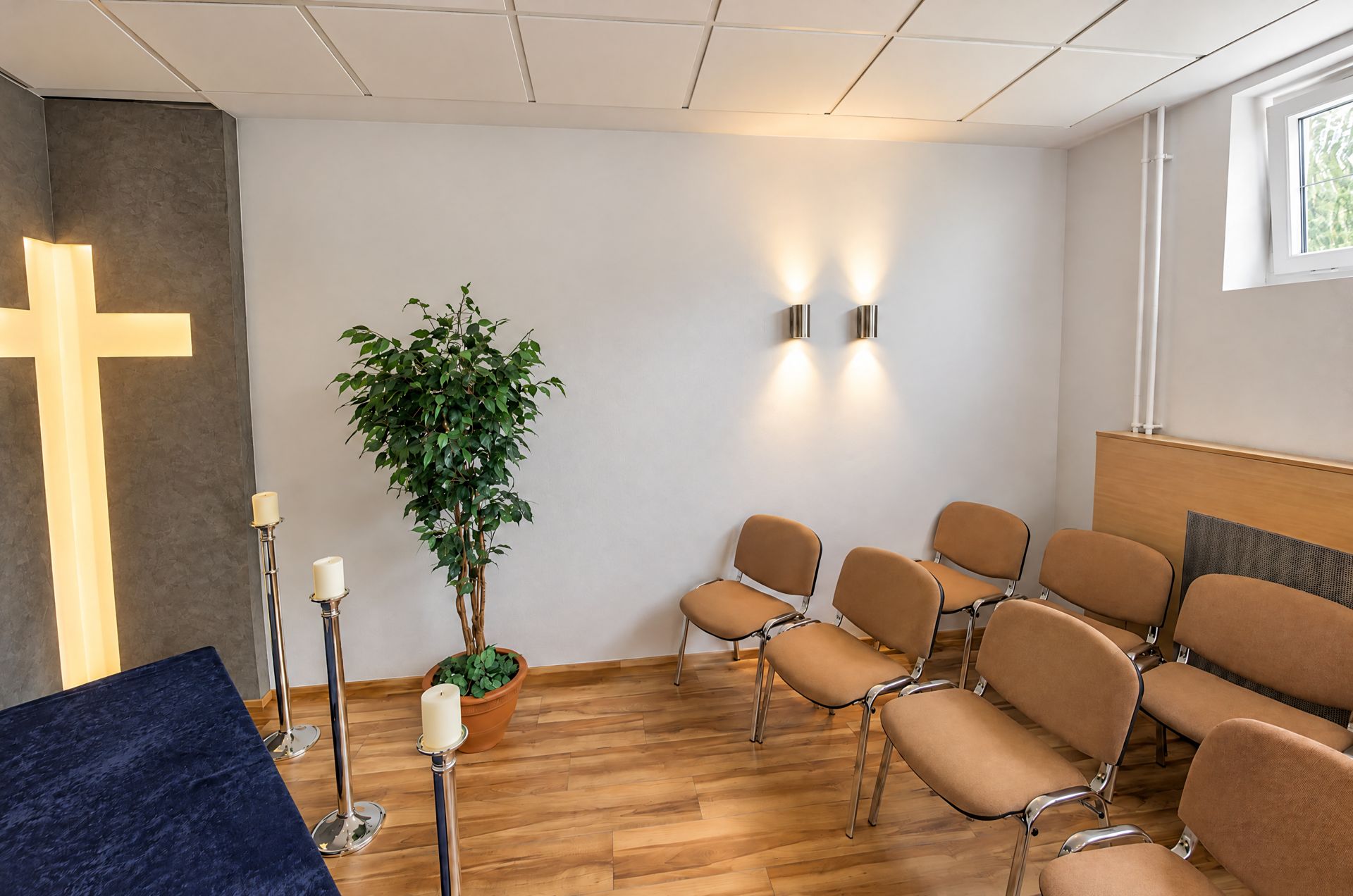 Trauer- und Abschiedsraum mit beleuchtetem Kreuz und Stuhlreihen